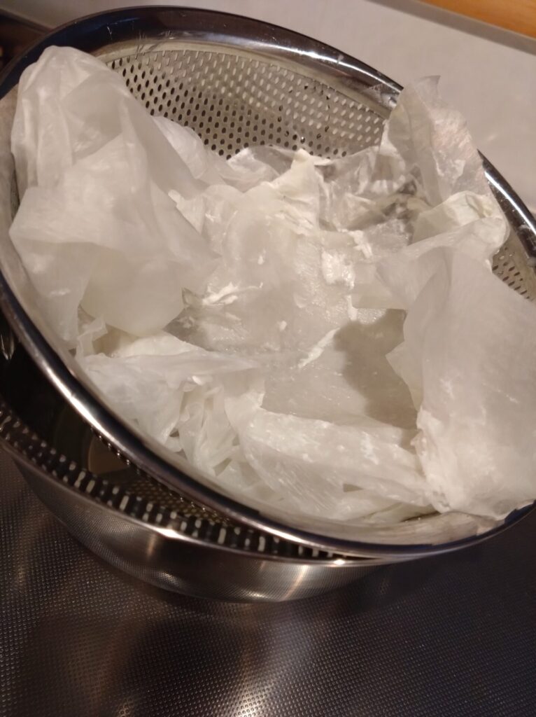 ヨーグルトの水切りをしてヨーグルトを取り出した直後のザルにおいてある濡れたキッチンペーパータオル