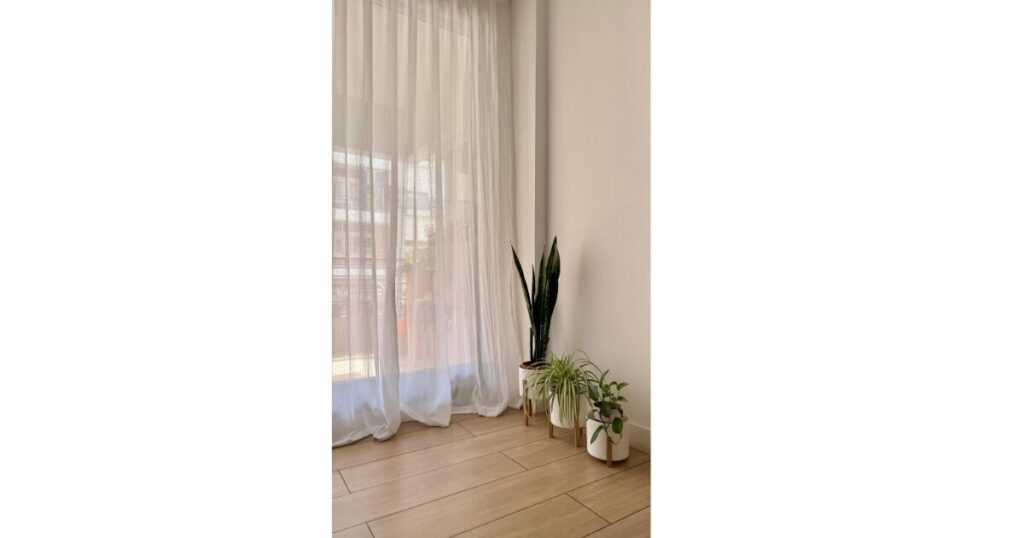 フローリングの部屋に長いレースのカーテンが掛かっている