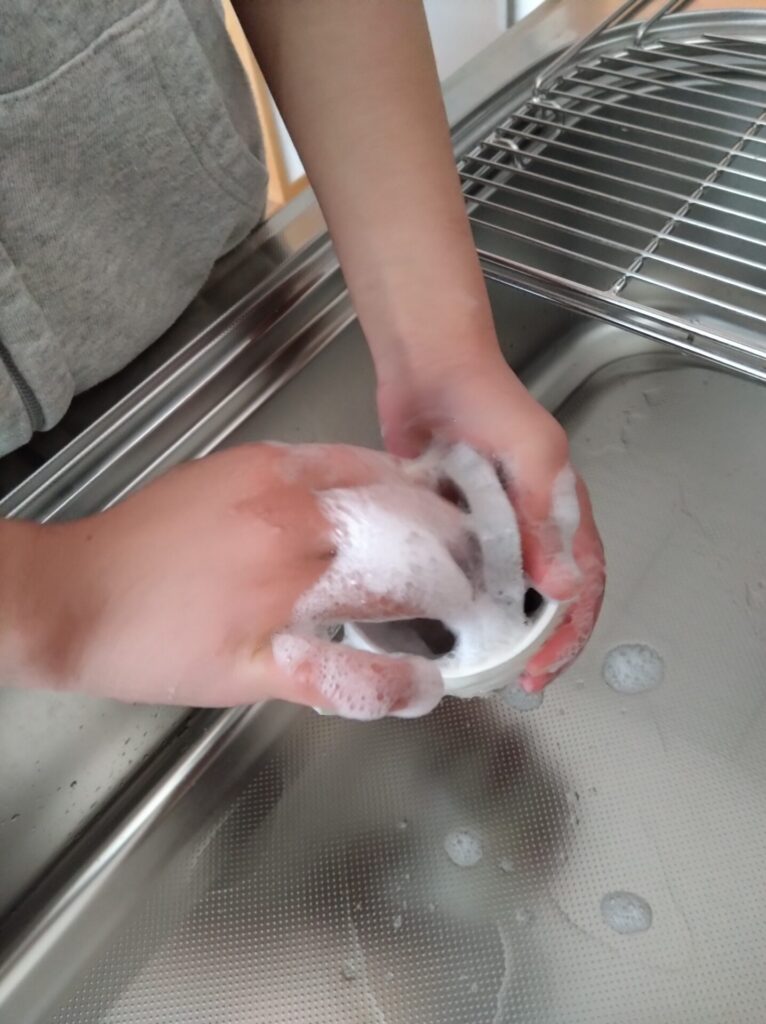 10代の子どもがマグカップを洗っている写真