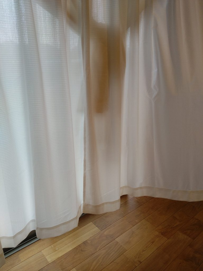 家の中から窓を写している。
外側のカーテンがくくってあり、内側のレースのカーテンは引いてある写真