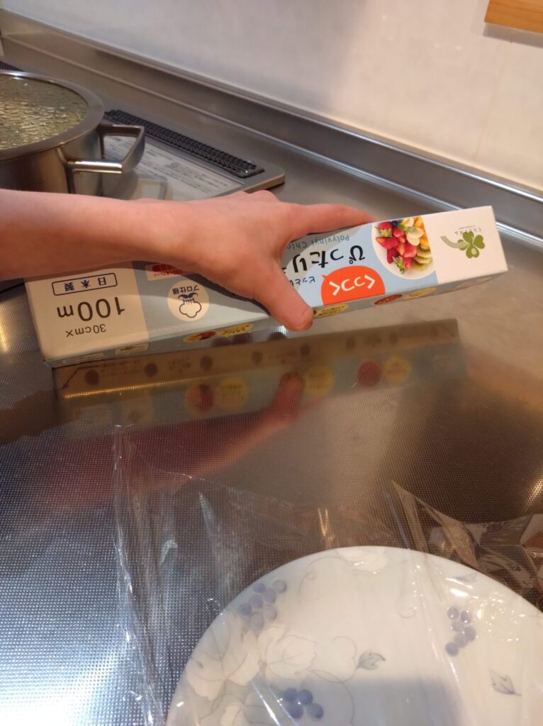 子どもが左手にラップを持ち箱を下側に回し切った直後で切れ端が斜めになっている