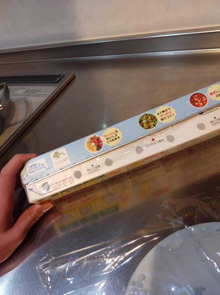 子どもが左手にラップの箱を持ってラップを切ったあとの切れ端の状態を見せている