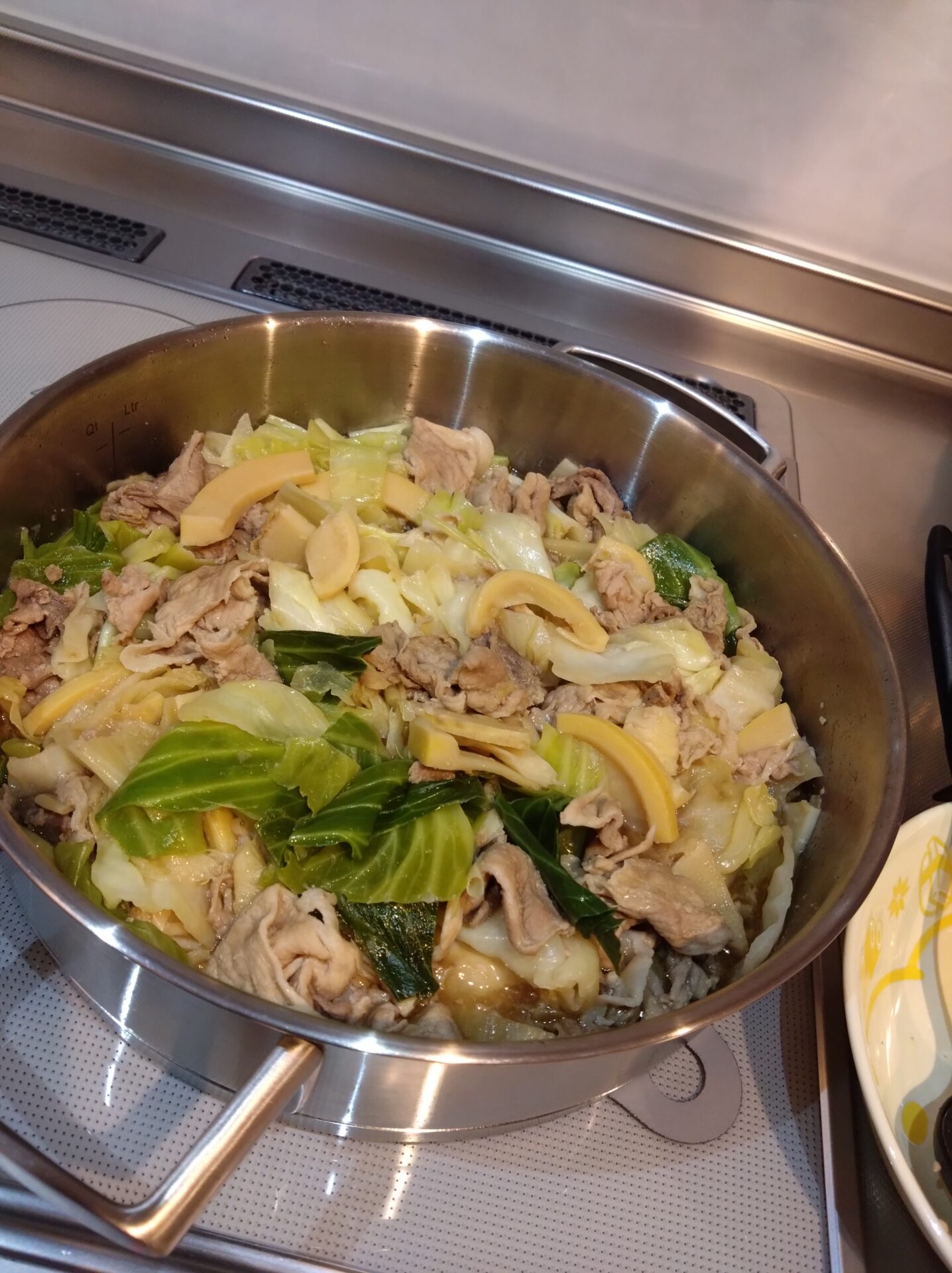 鍋の中に豚肉とタケノコ、冷凍キャベツを中華風に味付けした料理が入っている写真