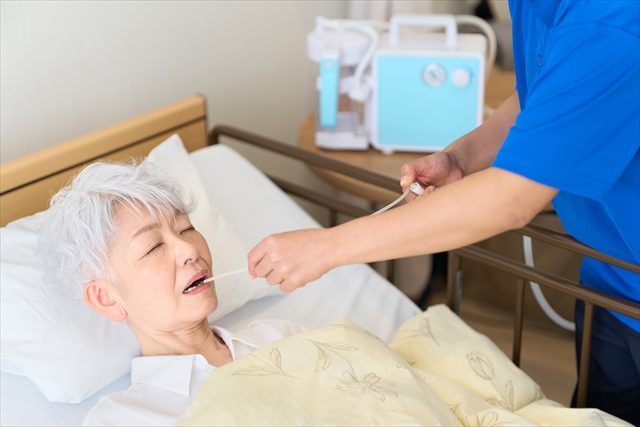 口腔から痰の吸引をしてもらっている女性