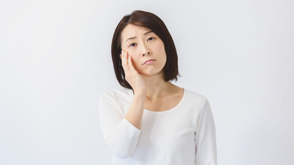 女性が首を傾げ頬に手を当てて心配そうにしている